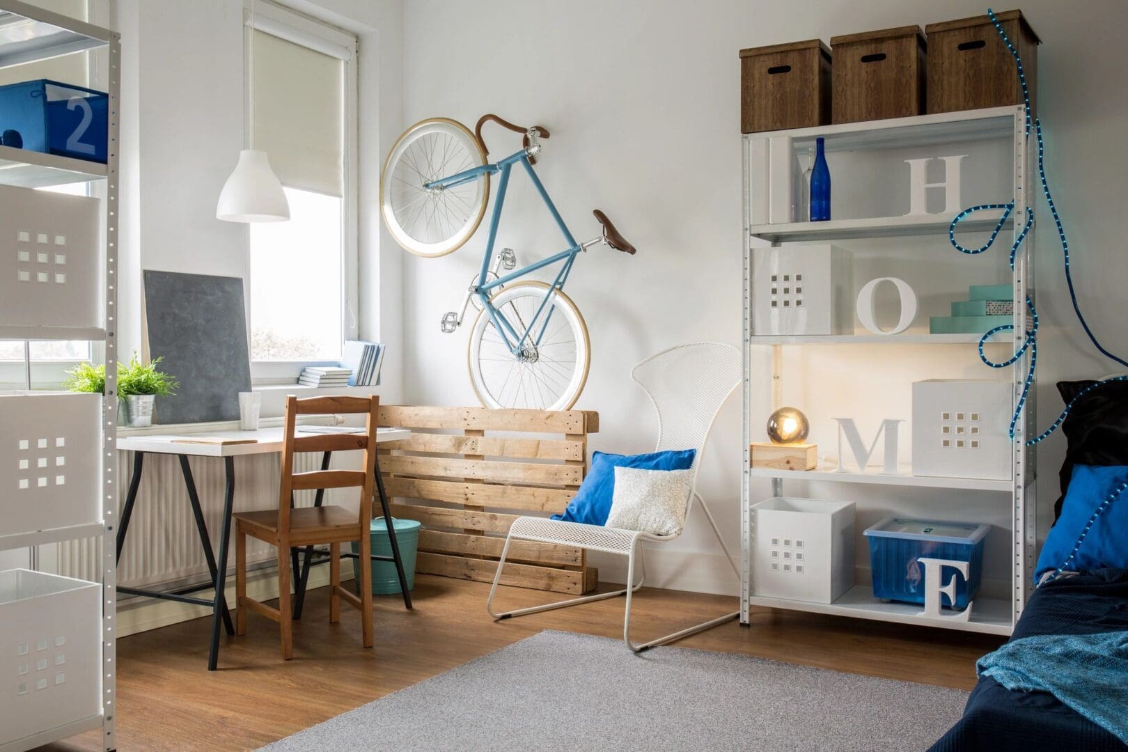 A room with a desk, chair and bicycle on the wall.
