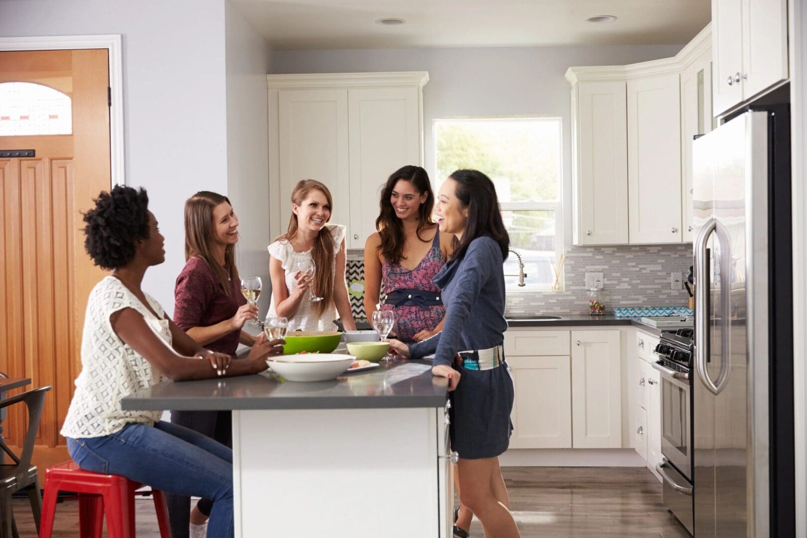 A group of people in the kitchen talking to each other.