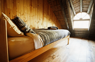 A closeup look at the bed in an attic and wooden floor